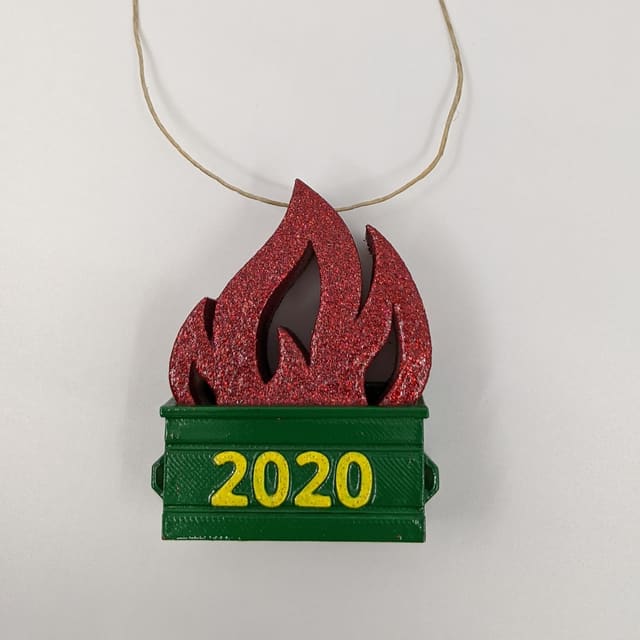 3D-printed dumpster fire ornament — a green dumpster reading 2020 with red glitter flames and a string hanger
