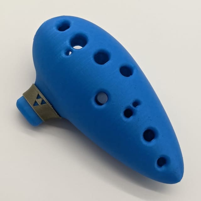 Blue 3D-printed 12-hole ocarina with a brass mouthpiece