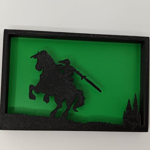 Black layered shadow box on green of a hero on horseback riding toward a castle