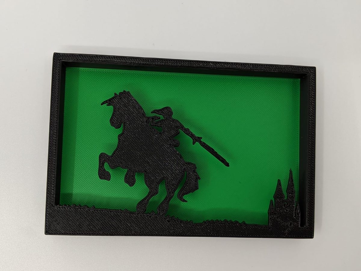 Black layered shadow box on green of a hero on horseback riding toward a castle