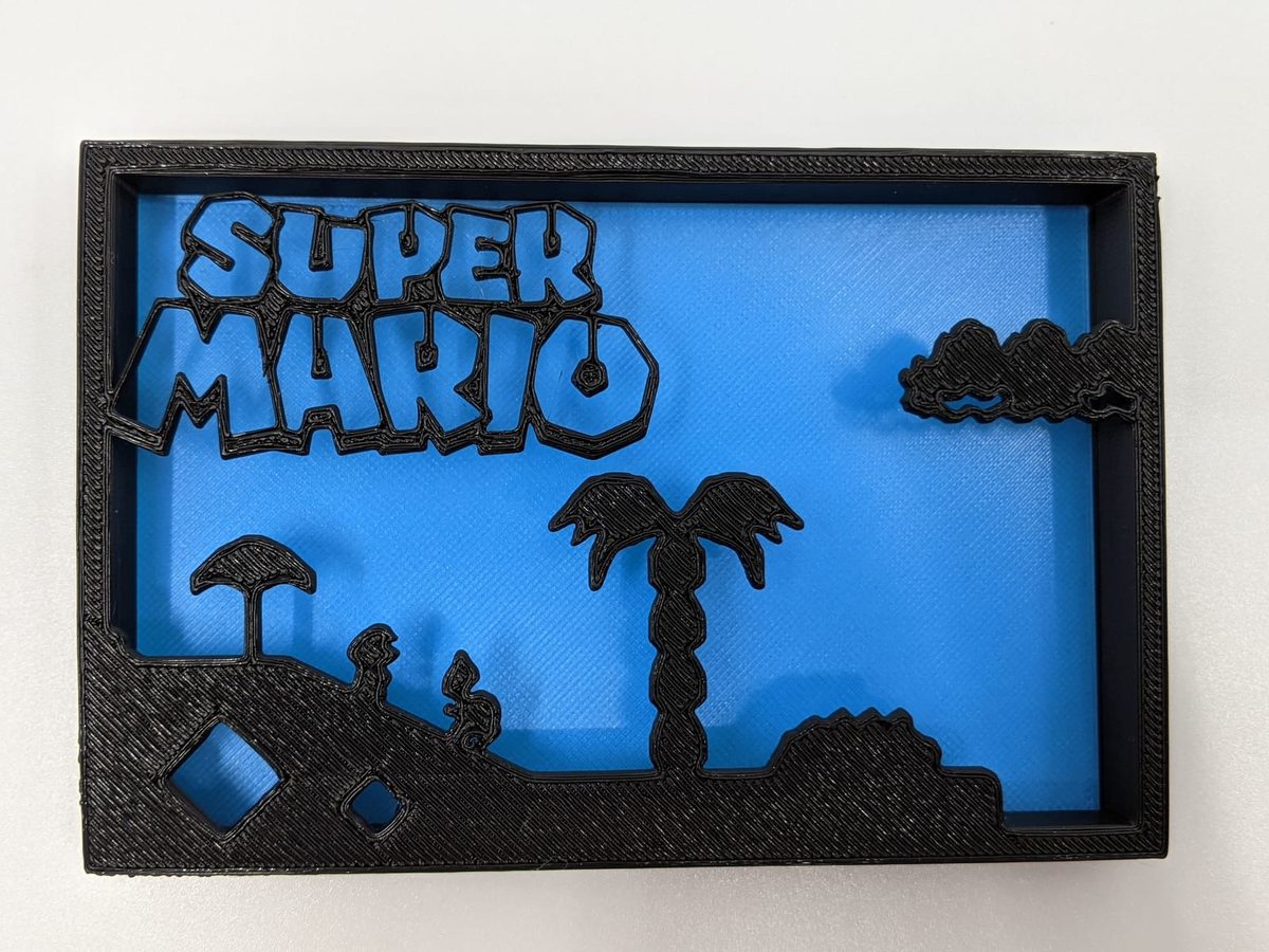 Black layered Super Mario shadow box on blue with clouds, a palm and the classic landscape