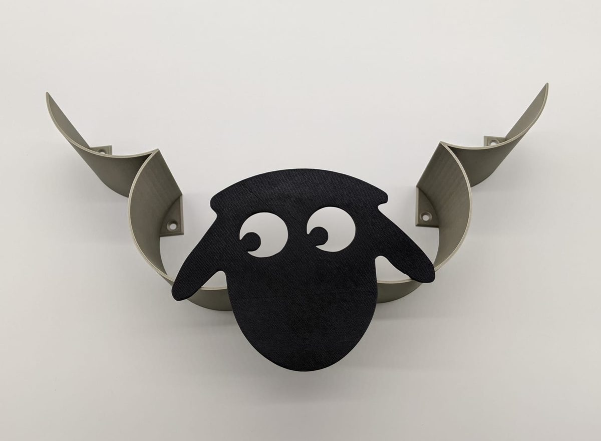 Floating wall shelf shaped like a black sheep with curled horns holding the ledge
