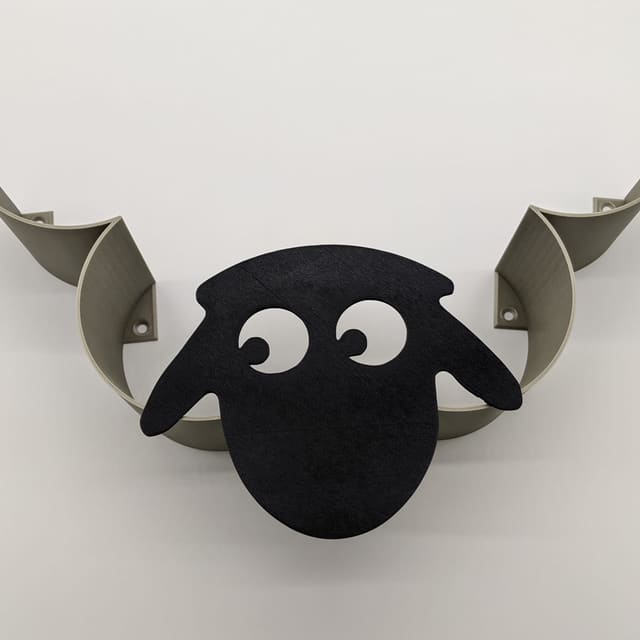 Floating wall shelf shaped like a black sheep with curled horns holding the ledge