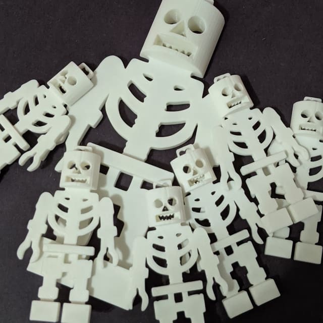 A pile of small white articulated 3D-printed skeletons, poseable at every joint