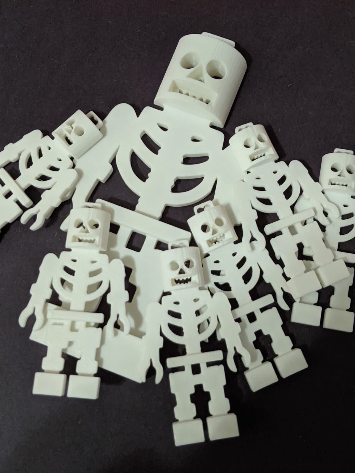 A pile of small white articulated 3D-printed skeletons, poseable at every joint