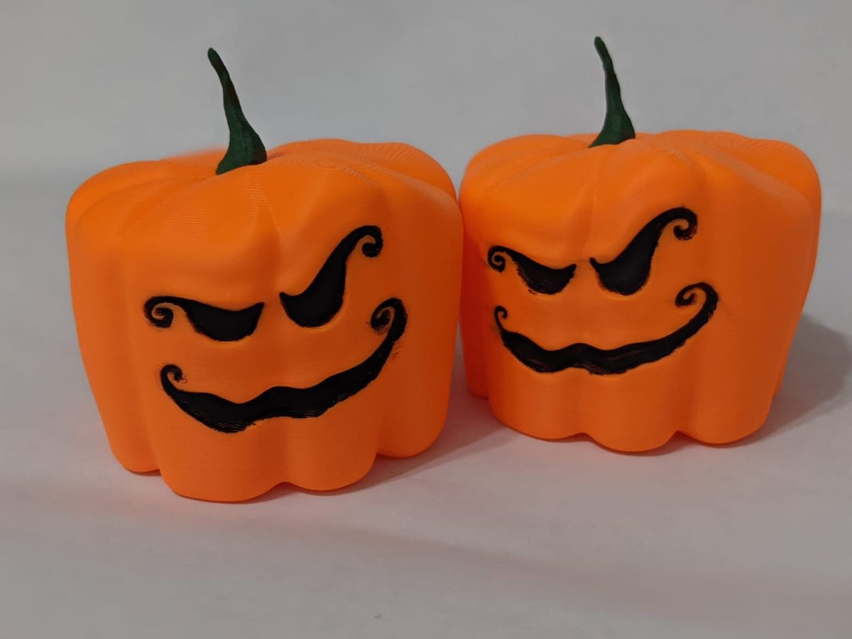 Two orange 3D-printed jack-o'-lantern boxes with grinning faces and green stem lids