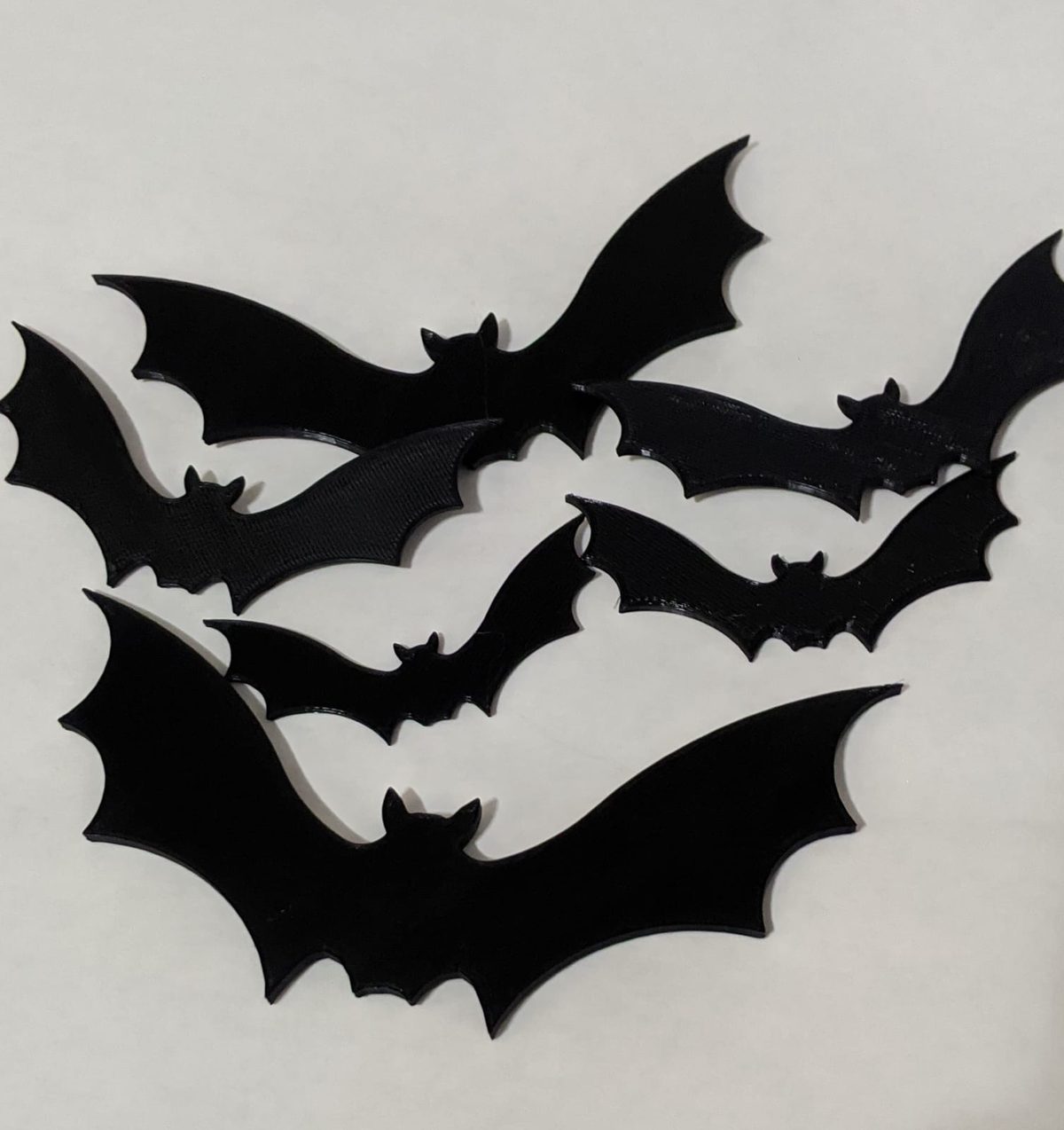 A set of flat black 3D-printed bat silhouettes in several sizes