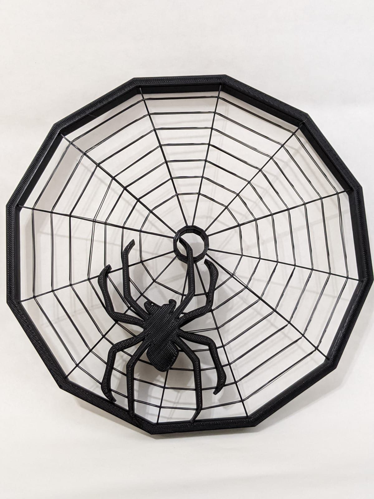 Black 3D-printed spider web dish with a large spider in the center