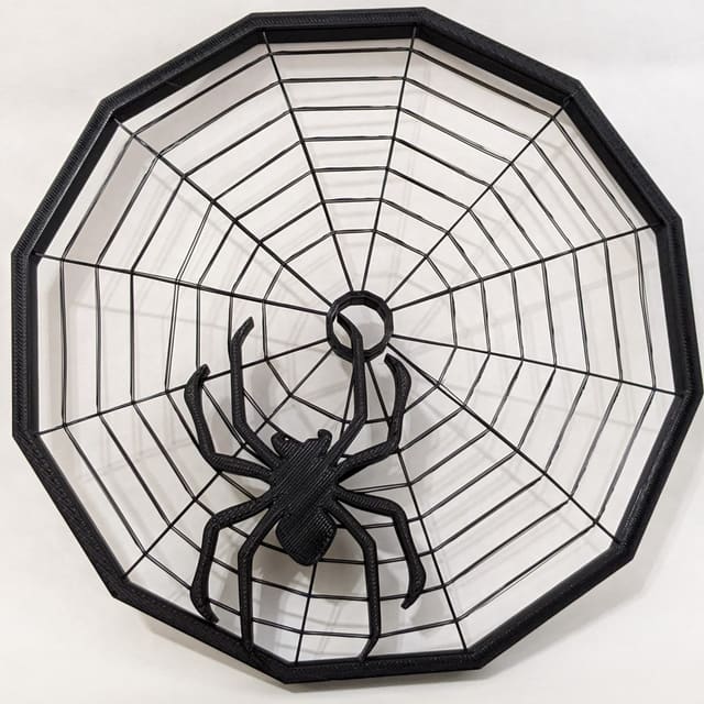 Black 3D-printed spider web dish with a large spider in the center